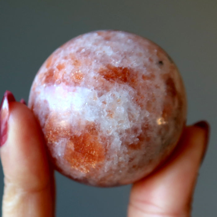 hand holding up a sunstone sphere