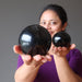 woman holding two black tourmaline spheres