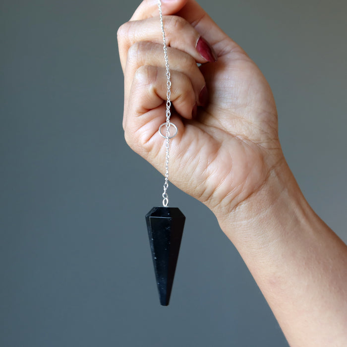 black tourmaline faceted pendulum in hand