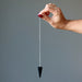 hand using black tourmaline faceted pendulum