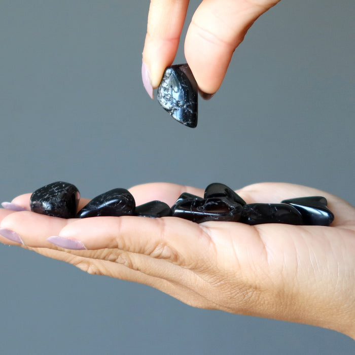 hand holding black tourmaline tumbled stones