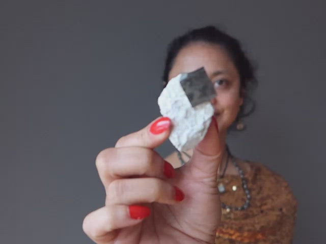 video on hand holding pyrite cube on white matrix