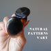 hand holding two large oval black agate ring to show natural patterns vary