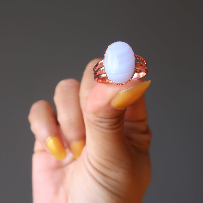 hand holding a wearing a blue lace agate oval copper adjustable ring