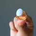 hand holding blue lace agate oval in gold tone adjustable ring