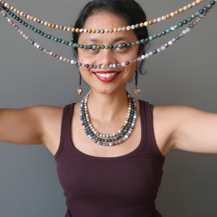 sheila of satin crystals wearing and holding agate medlne necklace