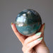 hand holding moss agate sphere