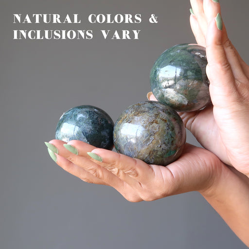 hand holding moss agate spheres to show natural colors and inclusions vary