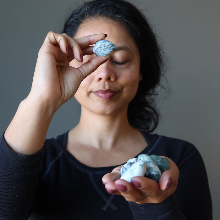 sheila of satin crystals meditating on Tree Agate Tumbled Stones on left hand and holding one Tree Agate Tumbled Stones in front of third eye