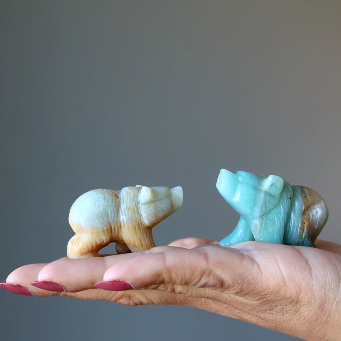 a model holding two a model holding a light brown and green Amazonite Polar Bear Figurines on her palm
