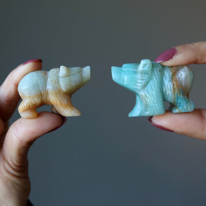 a model holding a light brown and green Amazonite Polar Bear Figurines on each hand
