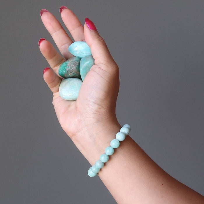 hand holding amazonite tumbled stones and wearing an amazonite bracelet
