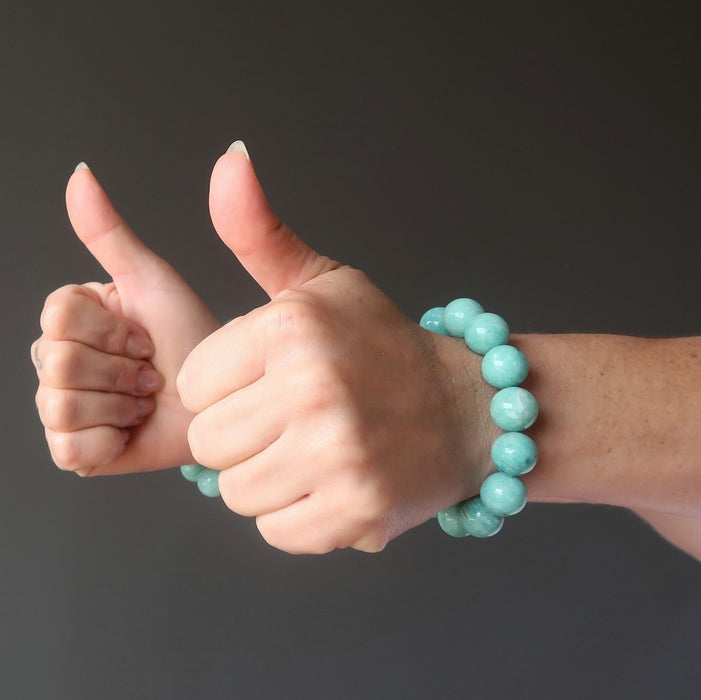 two thumbs up wearing amazonite bracelets on wrists