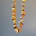 Display Yellow Orange Red Baltic Amber 10-18mm beads Knotted Necklace hanging on the gray background 