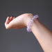 A woman's hand outstretched to show a round beaded purple ametrine crystal bracelet on her wrist