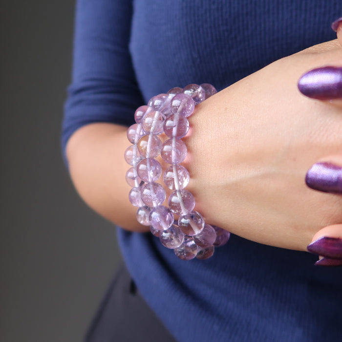 a woman wears three ametrine bead bracelets on her wrist to showcase a stack layer look