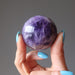 hand holding dark purple amethyst sphere