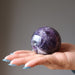 dark purple amethyst sphere in an open palm