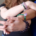 Two people have hands outstretched and show off several bracelets in malachite amethyst design and also in various amethyst designs