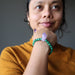 Sheila of Satin Crystals wears the Malachite Amethyst designer bracelet on her wrist while holding her head to her chin
