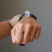 A female hand model displays the purple amethyst green malachite gemstone bracelet on her wrist