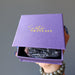 hand holding raw super 7 amethyst crystal point in a purple satin crystals gift box
