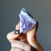 fingers holding amethyst cluster displaying the crystal points downward