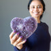 female holding sparkling purple amethyst geode heart cluster