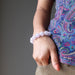 female with hand in pocket wearing lavender purple amethyst bracelet
