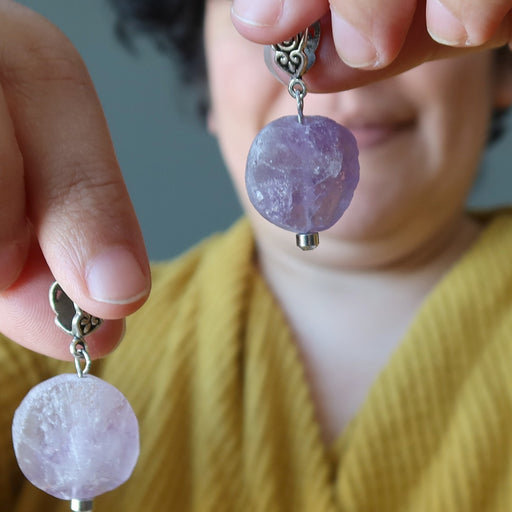 model holding 1.5 x 0.8 inches Raw Purple round Amethyst Pendants in each hand 