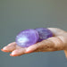 pair of purple amethyst polished ovalish palm stones in palm of hand