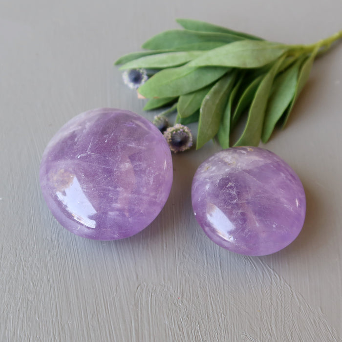 two purple amethyst polished palm stones of different sizes