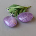two purple amethyst polished palm stones of different sizes and flowers