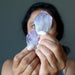 sheila of satin crystals holding two raw purple amethyst points with her finger tips