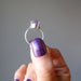 holding a faceted oval amethyst gemstone in silver ring