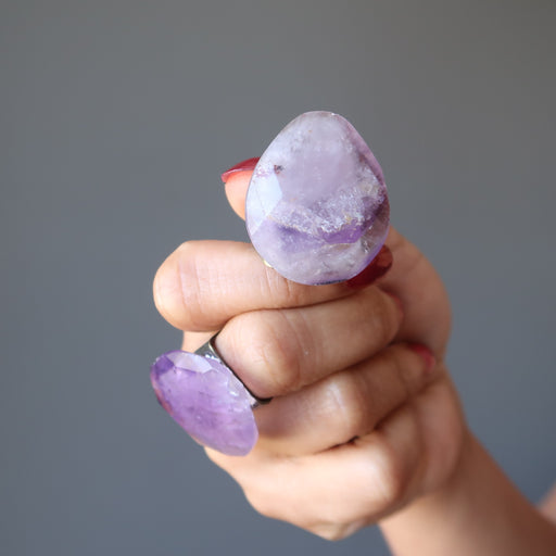model wearing pear shaped amethyst ring and holding another ring
