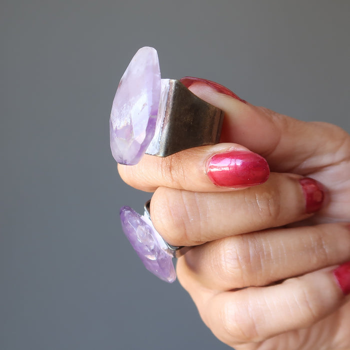 model wearing a pear shaped amethyst ring and holding another