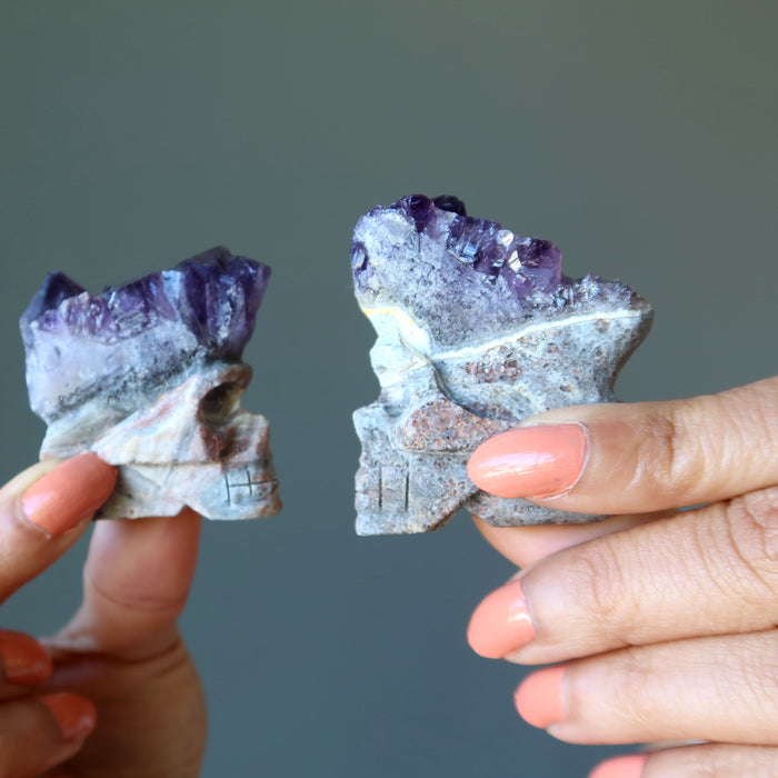 hand holding skull carved from an amethyst geodes