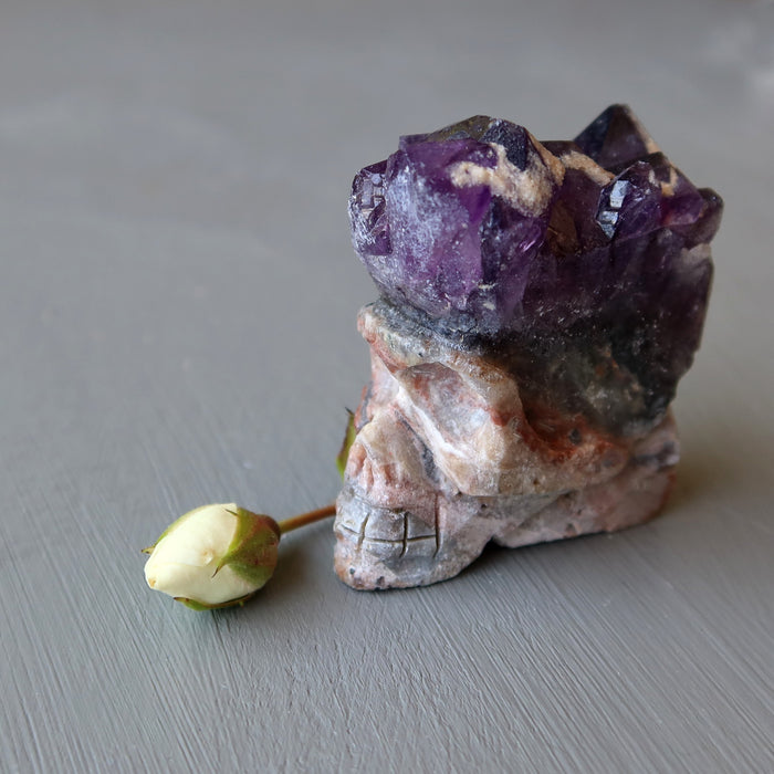 skull carved from an amethyst geode and rose bud