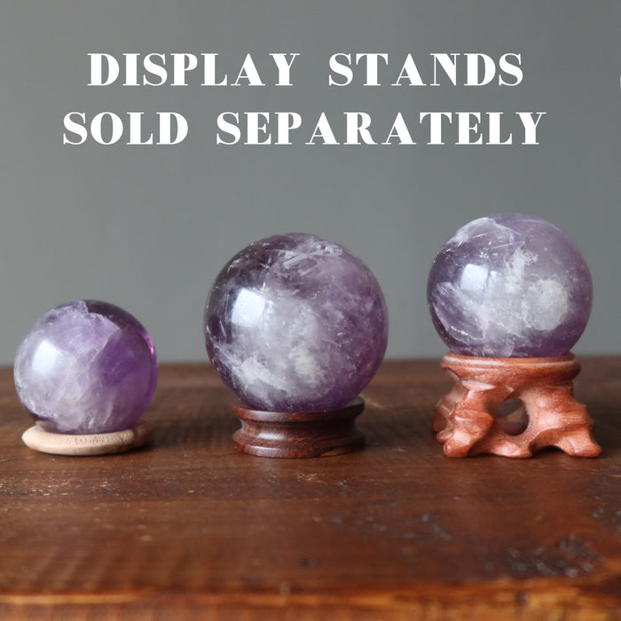 three amethyst crystal balls on wood stands sold separately