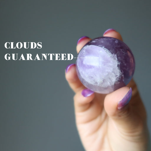 hand holding amethyst sphere guaranteeing white clouds
