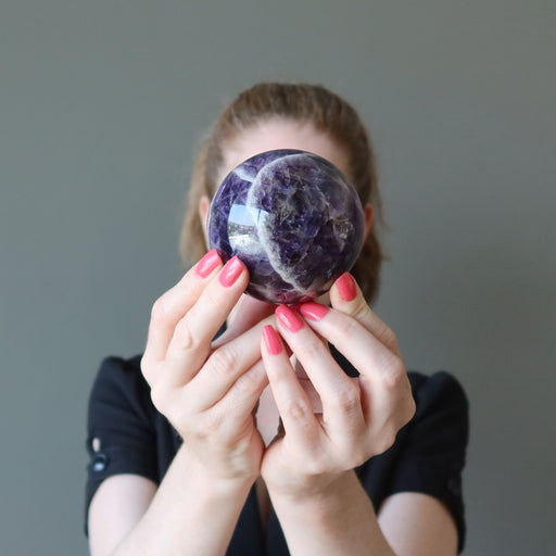 jamie of satin crystals holding up a chevron amethyst sphere