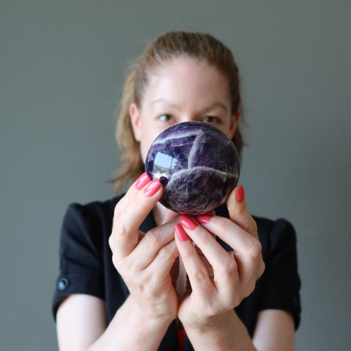 jamie of satin crystals holding up a chevron amethyst sphere