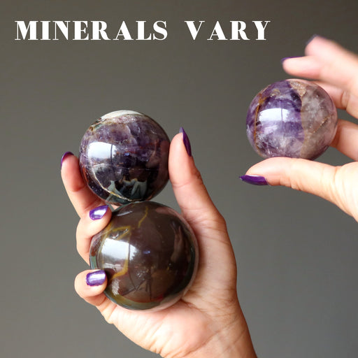 hand holding 3 amethyst mineral mania spheres to show minerals vary