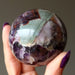 hand holding mineral amethyst sphere