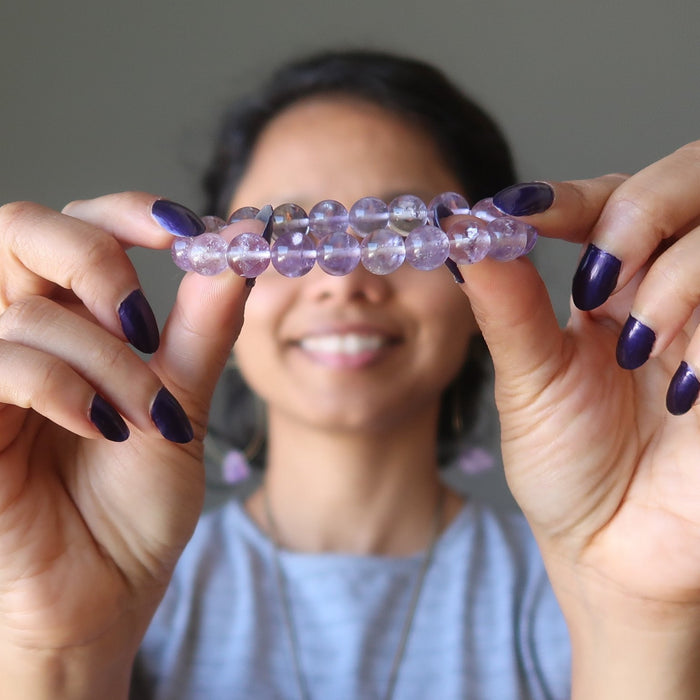 Sheila Satin of Satin Crystals holds out a clear purple Ametrine stretch bracelet