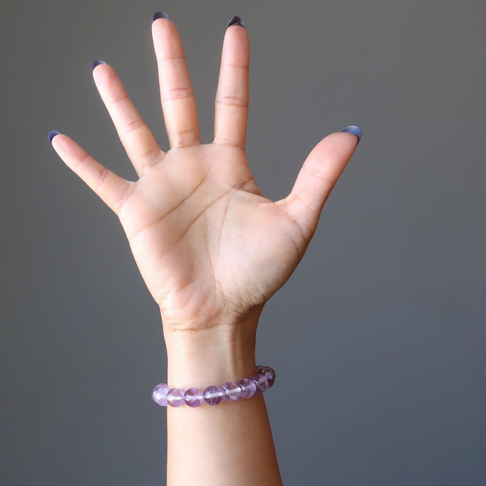A woman's hand outstretched to show a round beaded purple ametrine crystal bracelet on her wrist