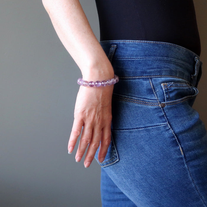 a woman holding the purple ametrine bead bracelet against her jeans