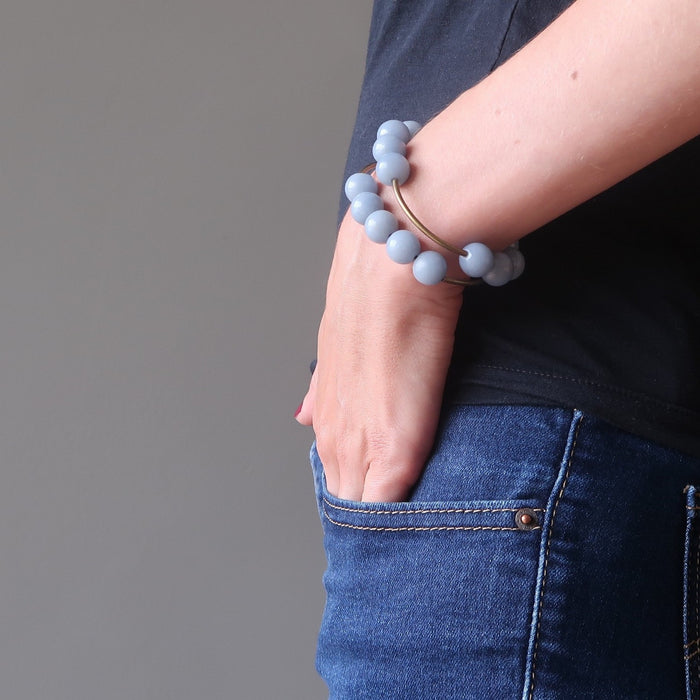 female hand in jeans pocket modeling angelite brass stretch bracelets