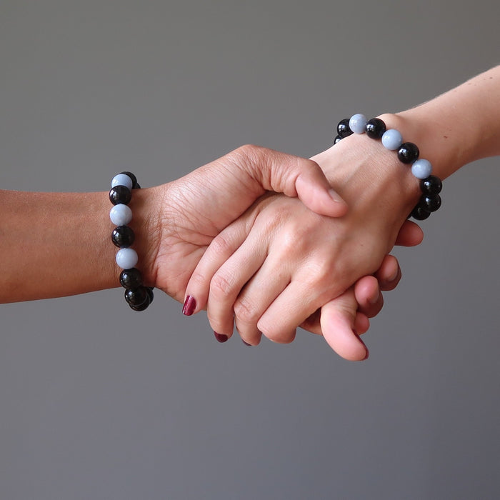 man and woman holding hands wearing rainbow obsidian angelite bracelets